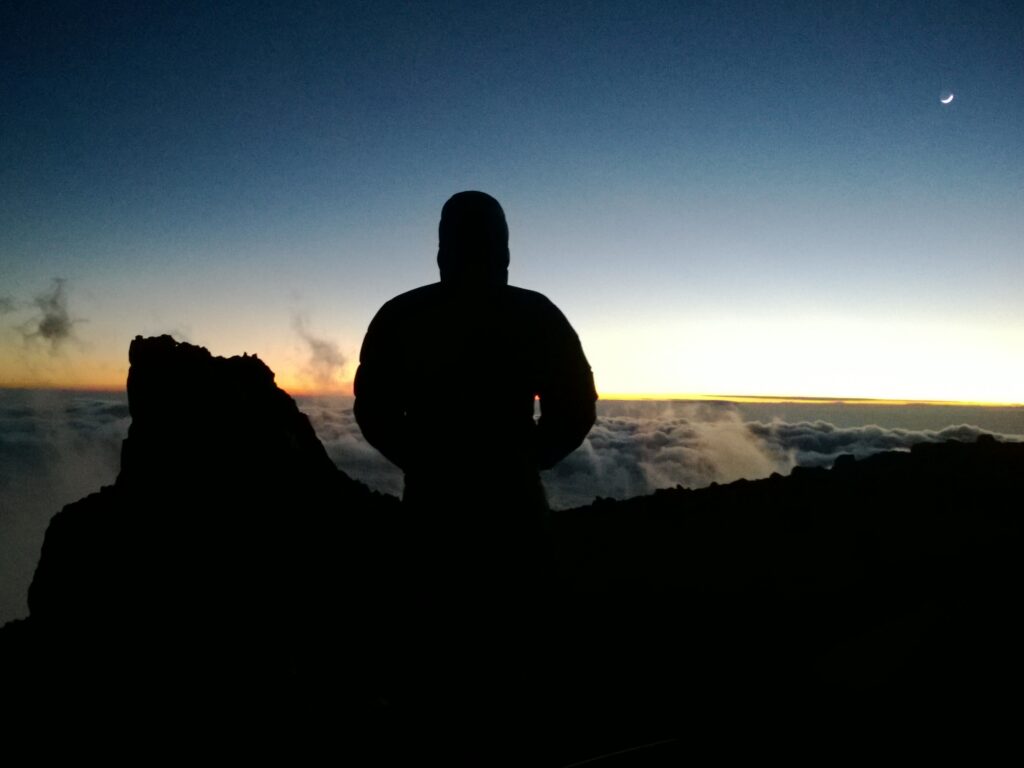 Example of highlight clipping. A man at dusk facing a sea of cloud on Mount Kilimandjaro.